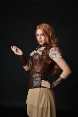 portrait of a red haired girl wearing steampunk costume. black studio background.