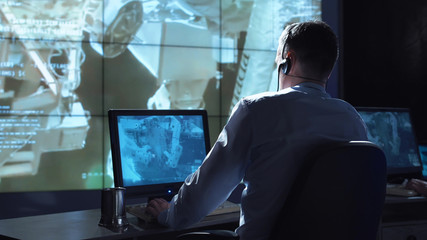 Movement shot back view of man working on space mission in control center. Elements of this image...