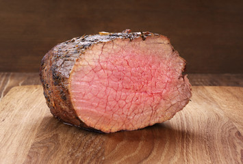 Baked meat on a wooden background. Roast beef.