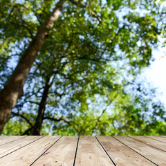 Wood table top on blur green background of trees in the park.