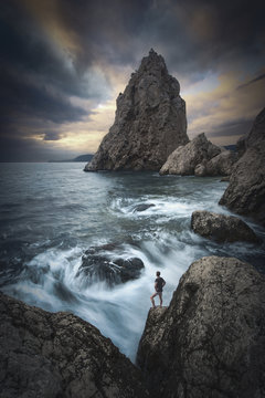 Man on a cliffs edge above the sea. Instagram stylization