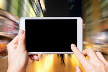 fingers touching computer tablet on shopping street in the evening, business background