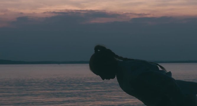 MED Caucasian professional female athlete performing traditional karate bow. Sunset over large lake in the background.. 4K UHD, 60 FPS SLO MO