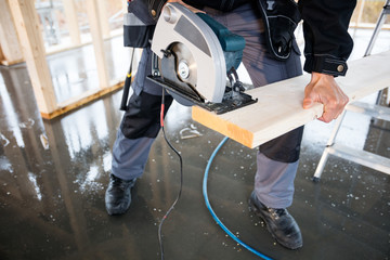 Low Section Of Carpenter Using Electric Saw To Cut Wood