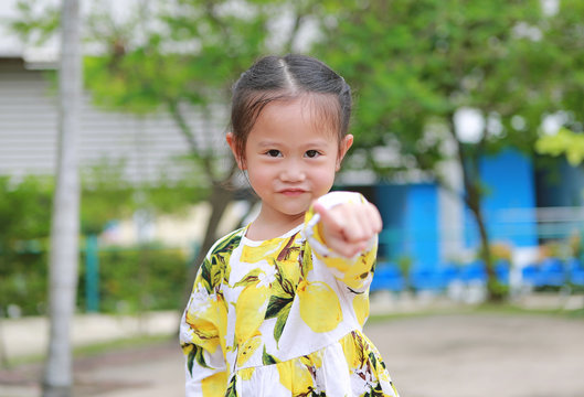 Cute Smiling Little Girl Pointing At You In The Garden.