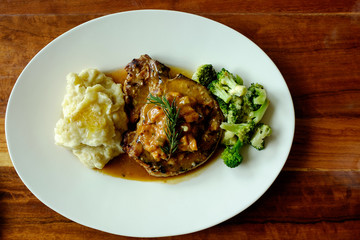 Top view of delicious grilled pork chops with mash potato and steamed green broccoli on brown wood table