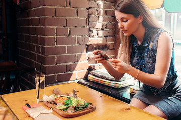 Young woman wearing casual clothes taking picture of her healthy lunch sitting on windowsill in...
