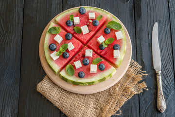 Sliced, juicy watermelon pizza with blueberries and cheese
