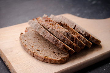 Slices of freshly baked dakr bread on the  wooden board