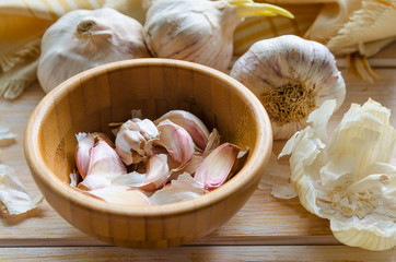 Organic garlic cloves in bamboo bowl on wooden table. Natural ingredients for healthy cooking  concept.