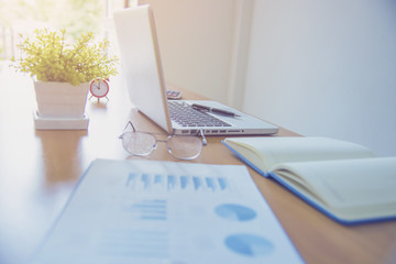 Image of coffee cup and laptop computer, notebook on desk of working businesspeople at meeting