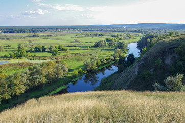 Fototapeta na wymiar Zigzag river flows between summer valleys