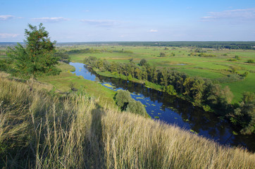 Zigzag river flows between summer valleys