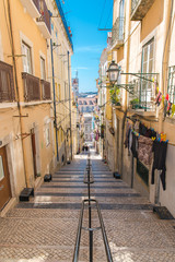 Fototapeta na wymiar Lisbon in Portugal, typical street, sloping alley with colored houses and typical pavement 