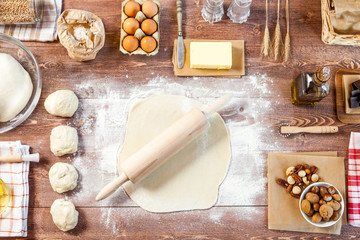 Rolled out dough on wooden table with rolling pin. Top view