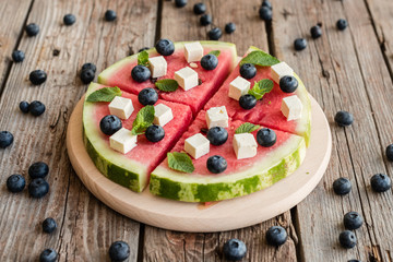 Sliced, juicy watermelon pizza with blueberries and cheese
