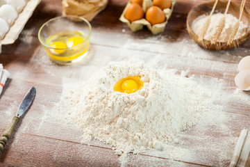 Egg yolk in flour on a wooden table in a bakery. Rural or rustic style.