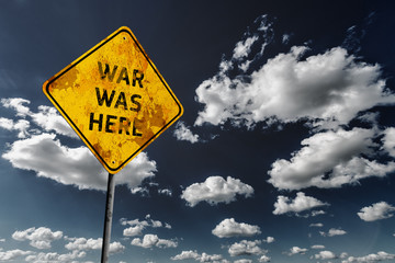 Dark blue cloudy sky and yellow faded road sign