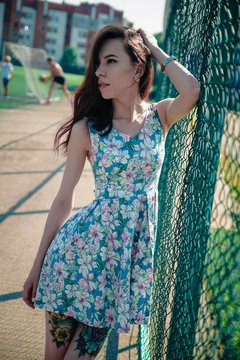 Beautiful young girl in a dress posing at the stadium