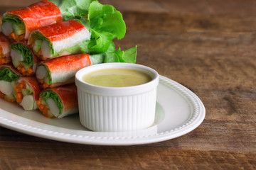 Fresh spring rolls with fresh vegetable and crab stick served with spicy salad cream dipping sauce. Rolls salad or fresh spring roll on white plate, healthy delicious food for appetizer or meal.