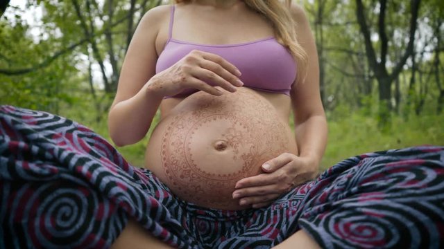 Pregnant girl with henna tattoo mehendi on her belly