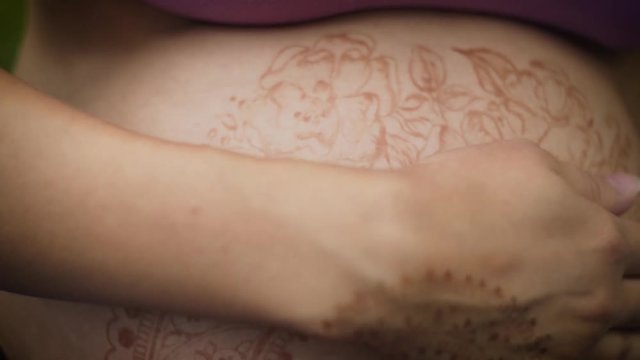 Pregnant girl with henna tattoo mehendi on her belly