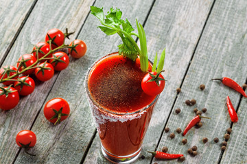 Glass of classic bloody mary cocktail on a rustic wooden table. Delicious alcoholic drink made of...