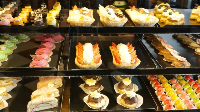 Different types of cakes in pastry shop glass display 