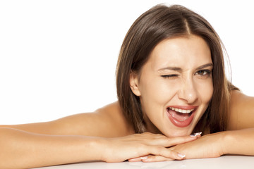 Fototapeta premium Portrait of a pretty young woman lying on a white background and winking