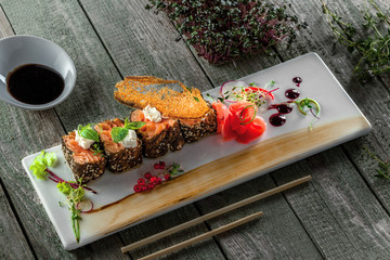 Traditional healthy Japanese meal sashimi made of salmon fish on a square plate. Fish rolls on a wooden table.