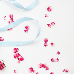 Delicate petals of a rose with a glass and a blue ribbon