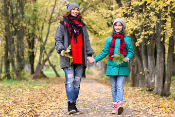 Mom and daughter on a walk in the autumn park