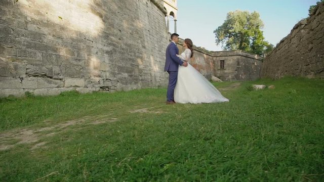 Lovely wedding couple coming to each other and embraces at castle. Slowly