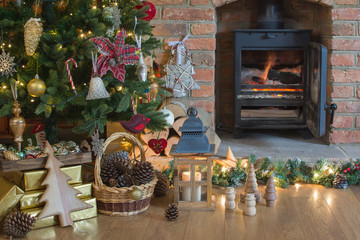 Beautiful Christmas setting, decorated lit up Christmas tree with baubles and ornaments, fireplace with woodburner , lantern, stars and garlands, selective focus