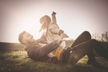 Happy father with his daughter outdoor. Happy father playing and lying on grass with his daughter.