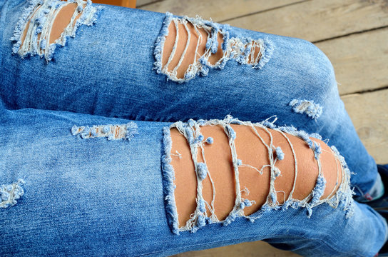 Ragged blue jeans on slender women's legs