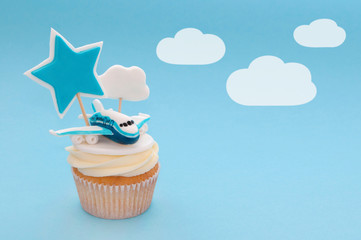 Cupcake for boy with whipped cream, decorated plane, toppers star and cloud on blue background....