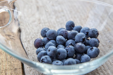 Fresh forest berry, blueberries in a glass plate on a wooden table