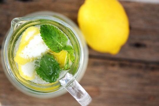 Jar of cool mint homemade lemonade on wooden table in a hot summer day