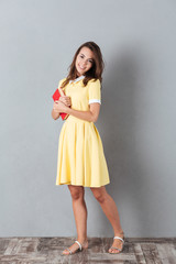 Full length of a smiling girl in dress holding book