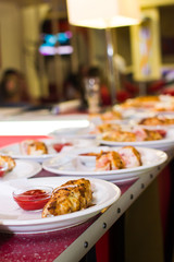 Fried meat rolls in a white plate on a bar rack