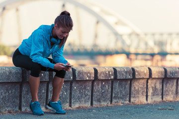 Young woman jogger using smart phone by the river