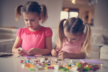 Fototapeta premium Girls playing at home. Girls playing with Bricks at home.