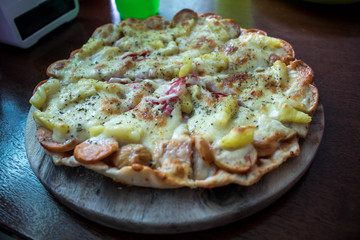Hot pizza with cheese melted on a rustic wooden table.