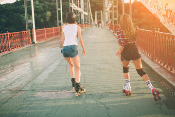 Two slim and sexy young women and roller skates. One female has an inline skates and the other has...
