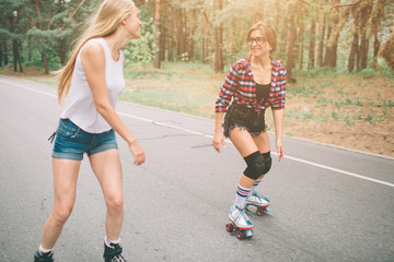 Two slim and sexy young women and roller skates. One female has an inline skates and the other has...