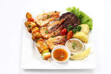 Skewered Chicken meat kebab Barbecue on wooden stick, Grilled Tiger Prawns & Beef Fillet Steak with Sauce & Lemon with Roasted Potato on White Square Plate on White Background. Menu Set Top side View.
