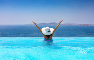 Frau im Pool genießt ihren Urlaub in einem Infinity Pool mit Aussicht