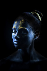 The creative makeup of the girl is covered with black paint and over the sparkles