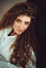 Beautiful stylish woman with curly hair in white sweatshirt